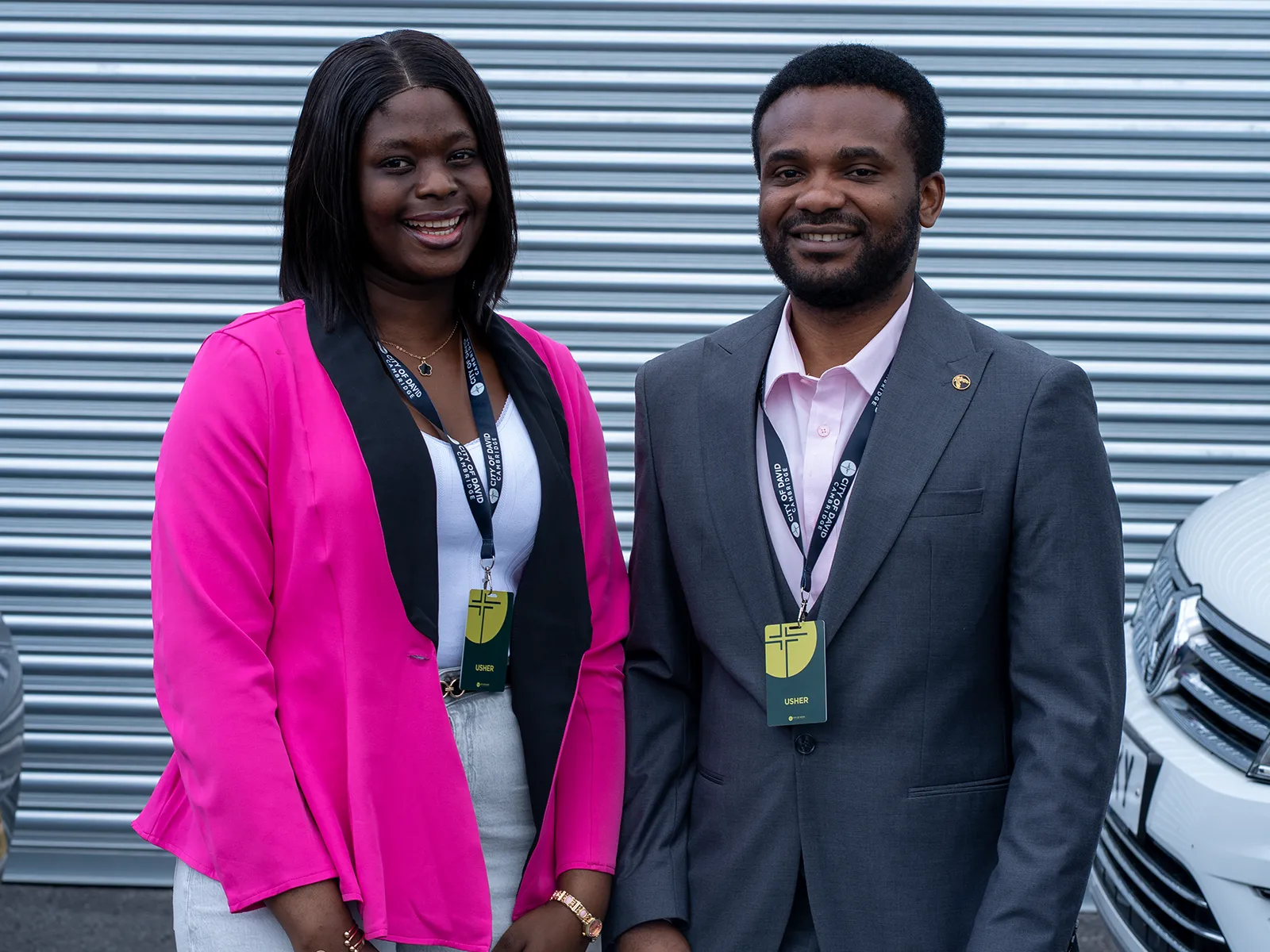 Two protocol team members in smart clothing and lanyards outside the church.
