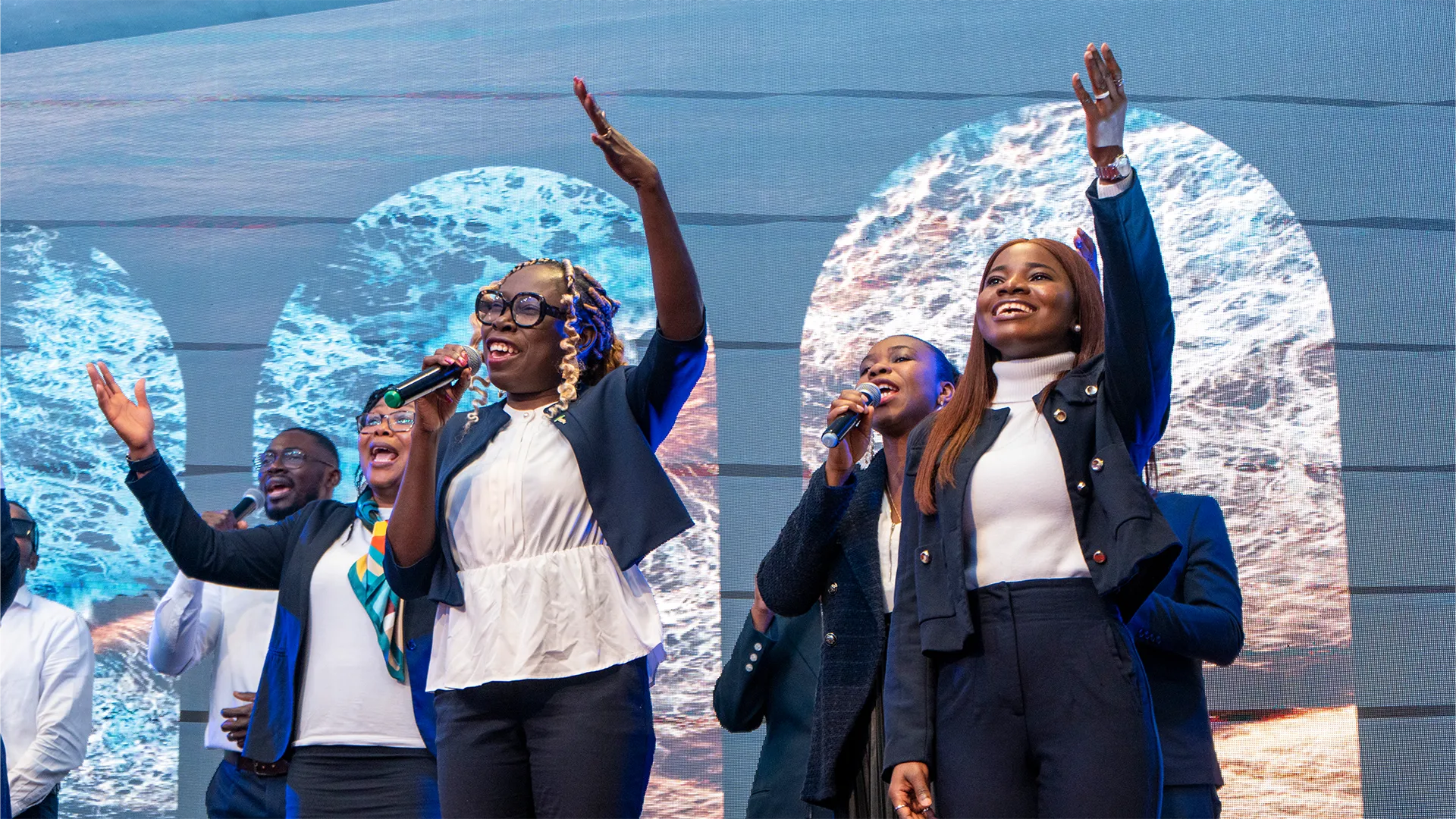 Worship team singing with raised hands during a City of David Cambridge service.